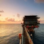 A breathtaking view of an oil platform on the ocean at sunset, showcasing industrial beauty.